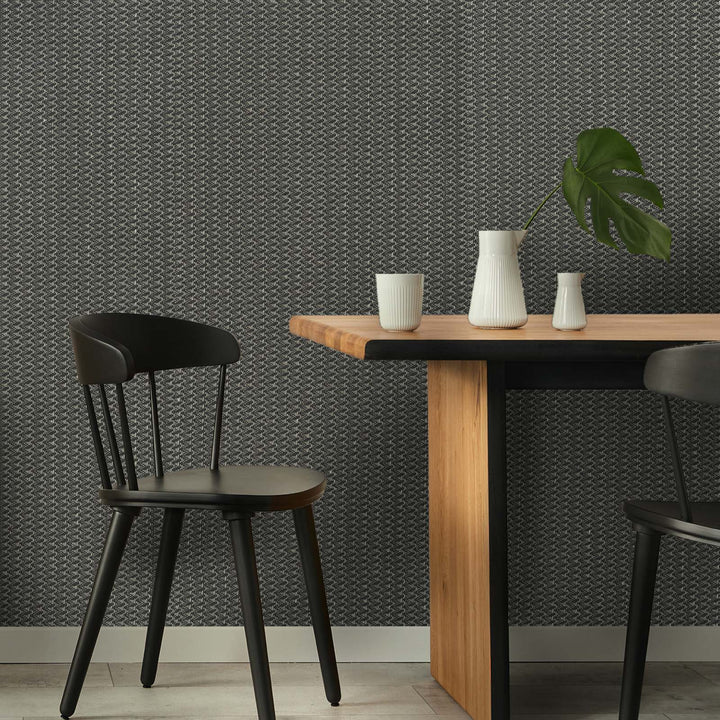 Dining area with wooden table, black chairs, and decorative items against a patterned wall.