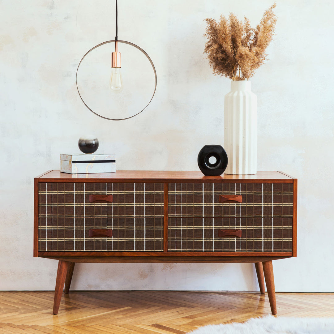 Wooden sideboard with grid design in a room with a white wall and wooden floor.