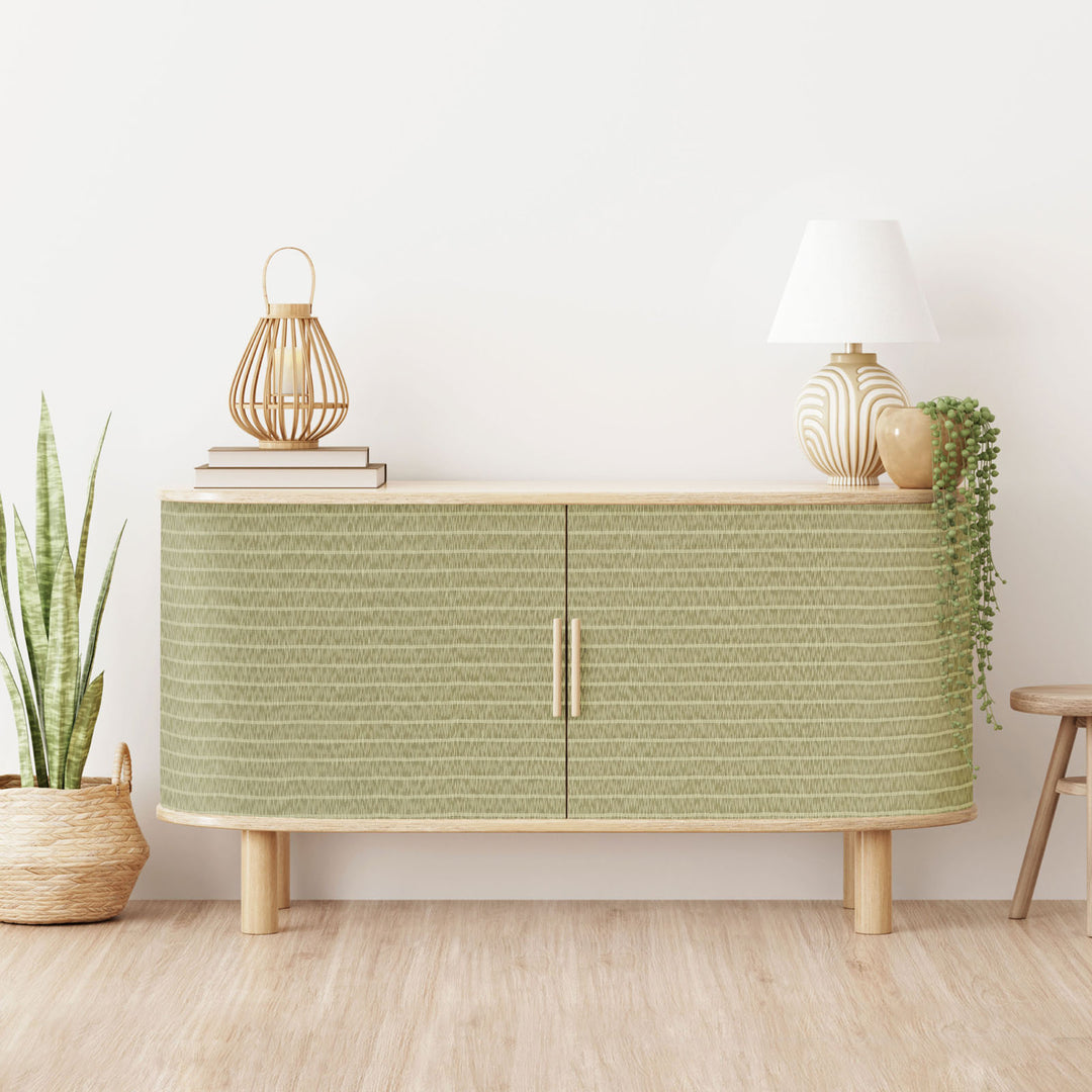 Green cabinet with decorative items in a room with plants and a stool.