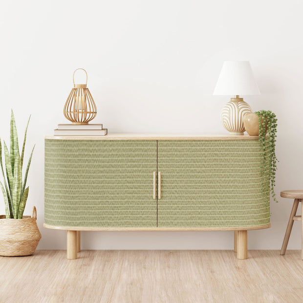 Green cabinet with decorative items in a room with plants and a stool.