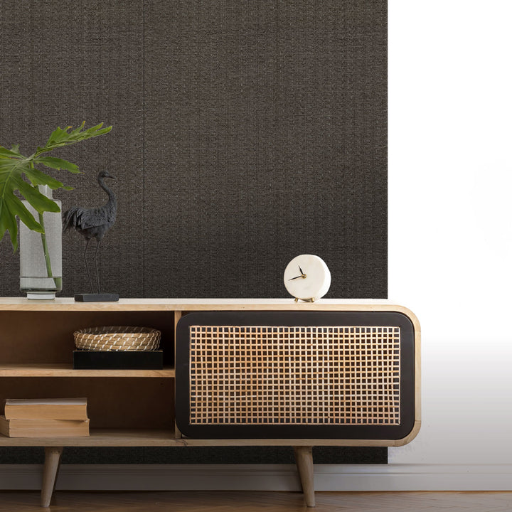 Wooden console table with wicker backrest against a dark wall