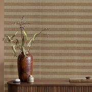 Decorative vase with branches on a wooden surface against a striped wallpaper background