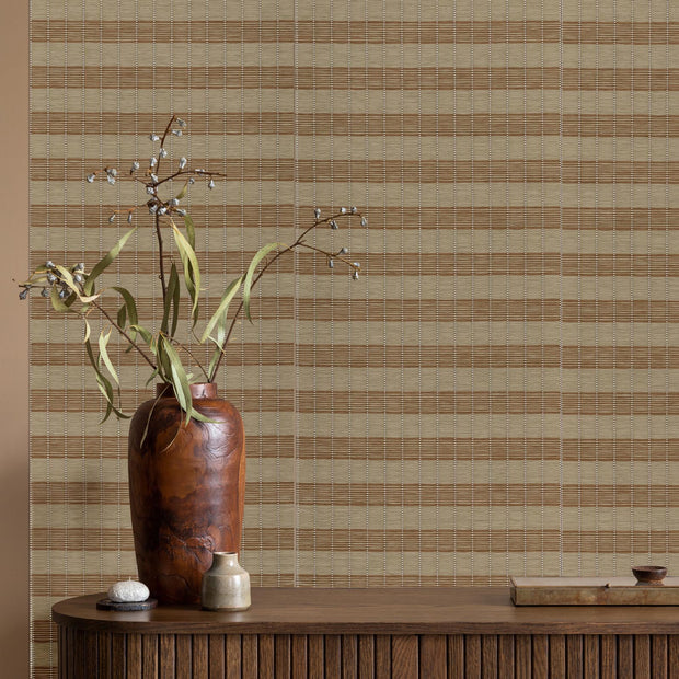 Decorative vase with branches on a wooden surface against a striped wallpaper background