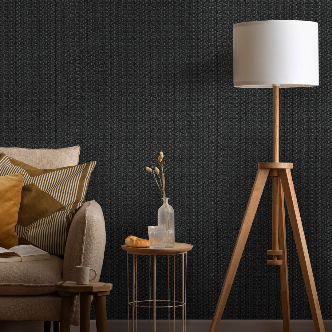 Living room with a tripod lamp, sofa, and side table against a dark textured wall.