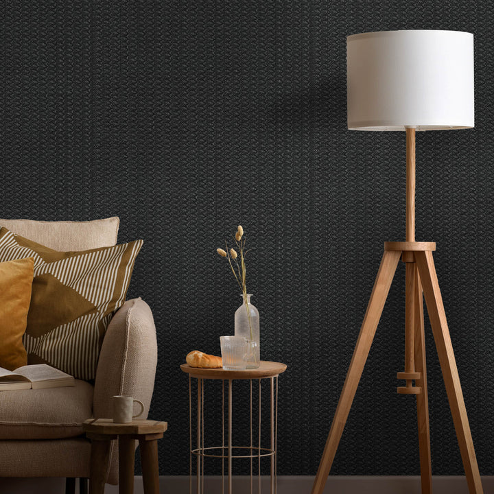 Living room with a tripod lamp, sofa, and side table against a dark textured wall.