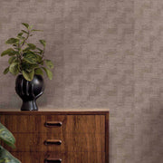 Wooden dresser with a black vase and plant against a textured brown wall