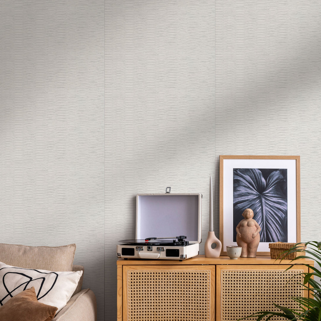 Living room with a rattan cabinet, record player, and framed artwork on a textured wall.