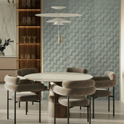 Modern dining room with a round table and chairs against a textured wall.