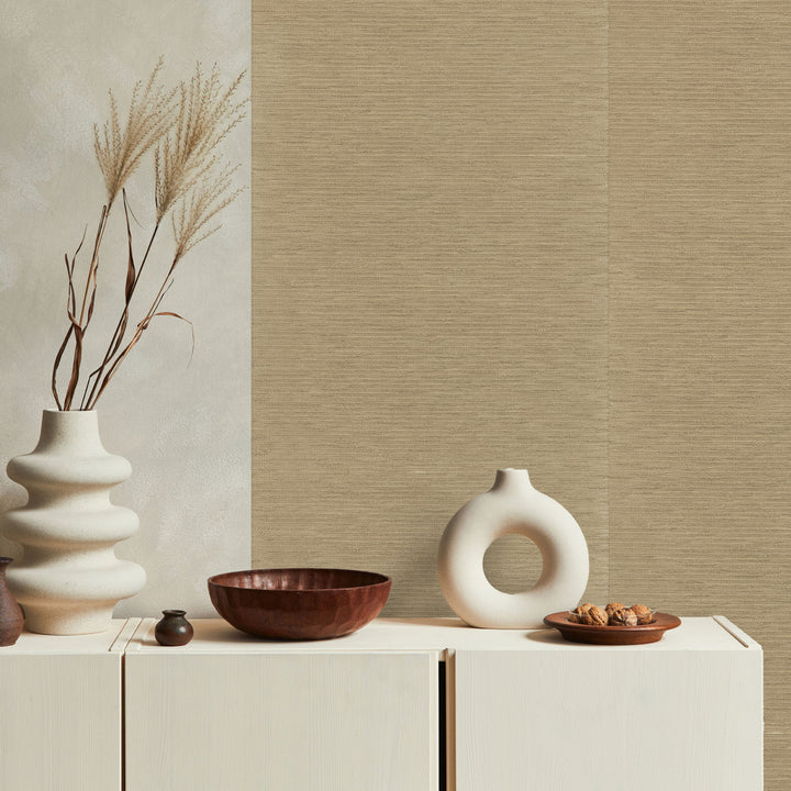 Decorative setting with vases and bowls on a cabinet against a textured wall.