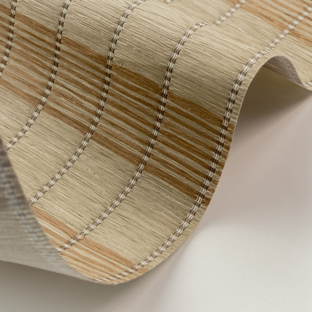 Close-up of woven fabric with brown and beige stripes on a neutral background