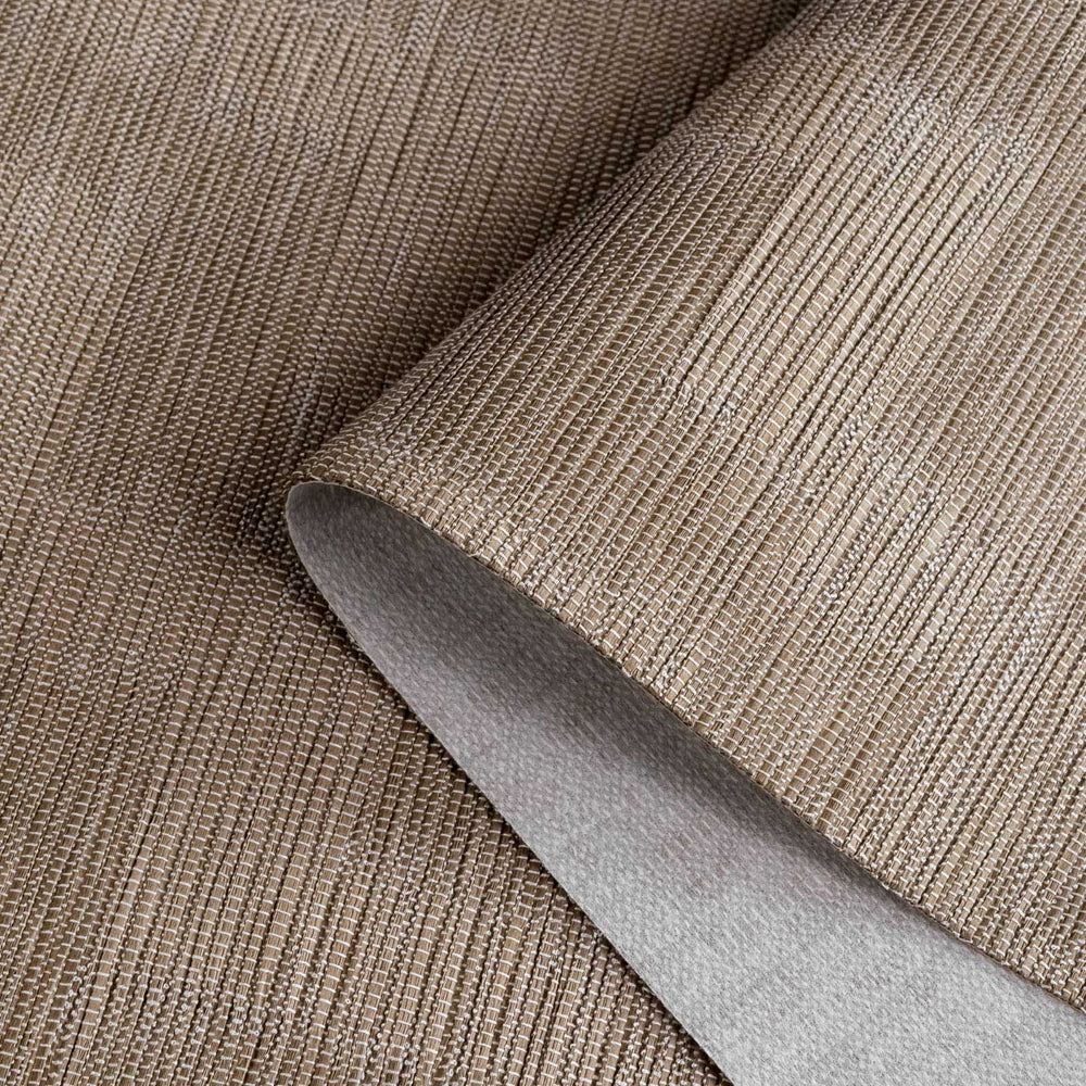Close-up of a roll of brown textured wallpaper with a knife blade on top.