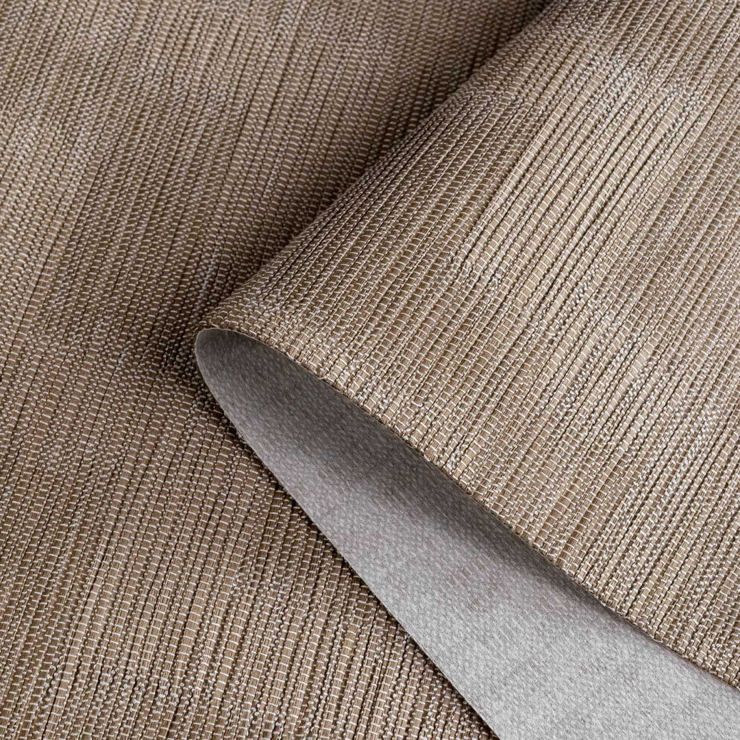 Close-up of a roll of brown textured wallpaper with a knife blade on top.