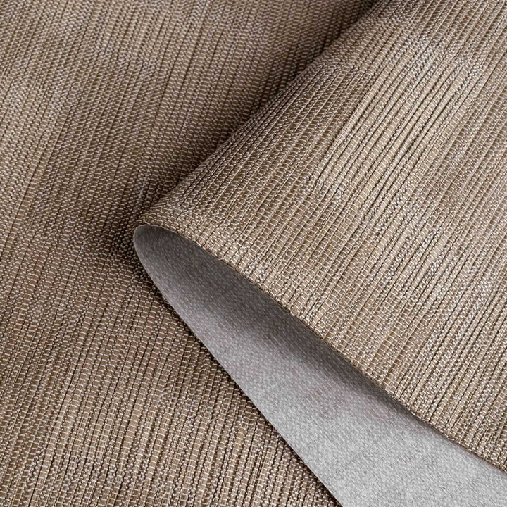 Close-up of a roll of brown textured wallpaper with a knife blade on top.