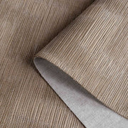 Close-up of a roll of brown textured wallpaper with a knife blade on top.
