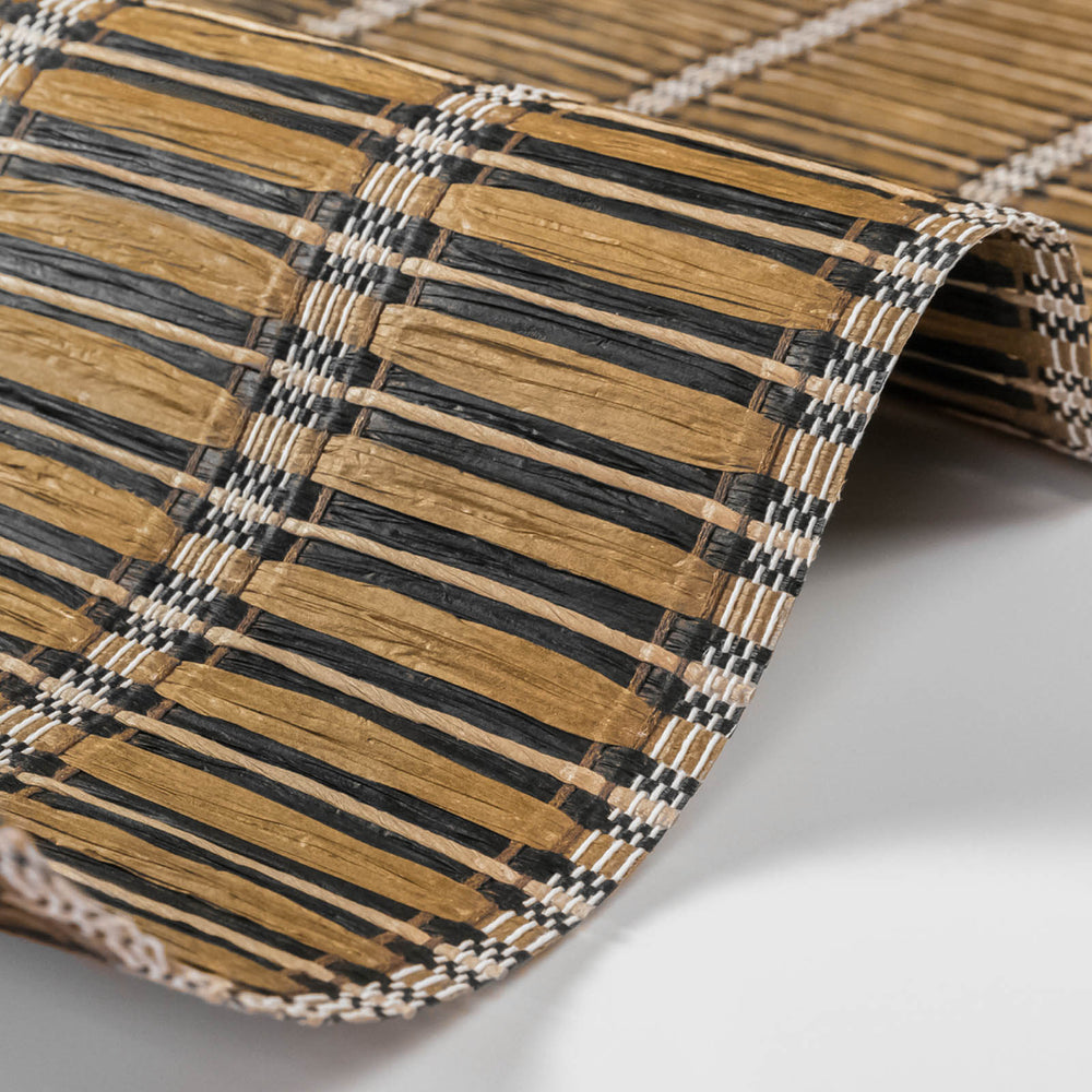 Close-up of a woven bamboo mat with black and beige stripes on a white background
