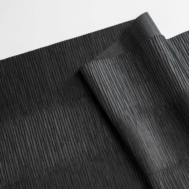 Close-up of black textured paper with a slight sheen on a light gray background