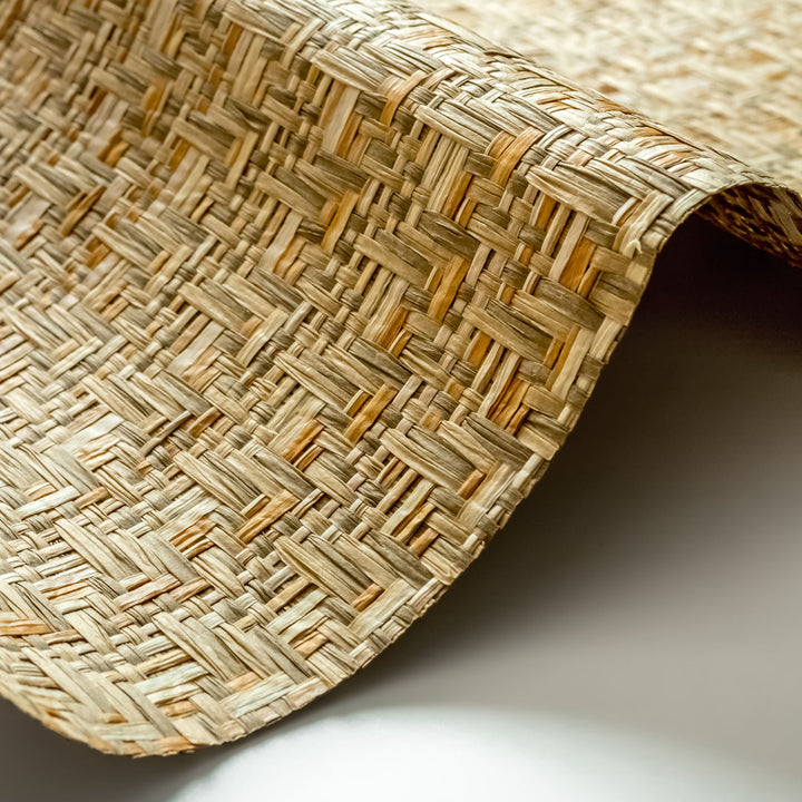 Close-up of woven natural fiber wallpaper with a textured basketweave pattern in earthy beige and tan tones.