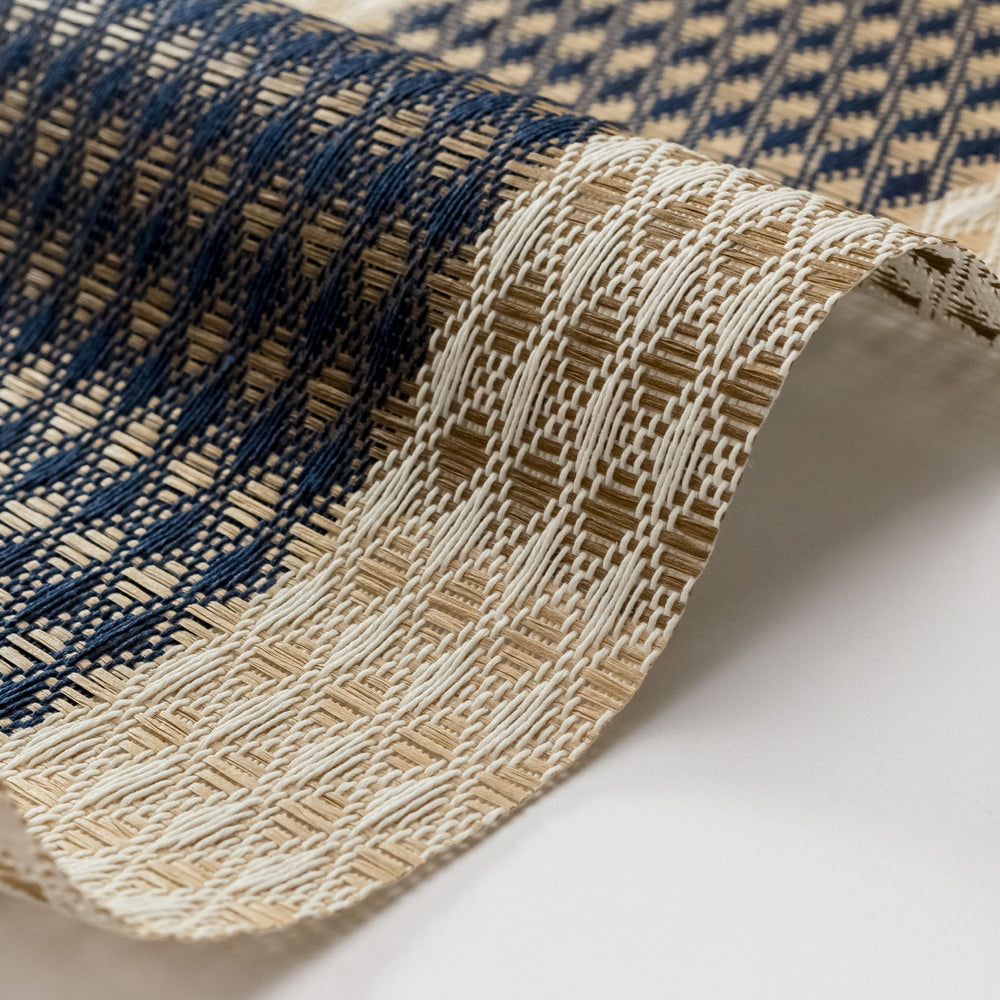 Close-up of a woven mat with blue and beige pattern on a white background