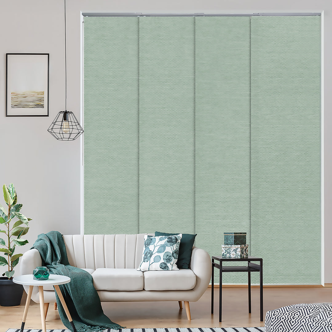 Living room with a white sofa, green cushions, and a plant, featuring a large window with green blinds.