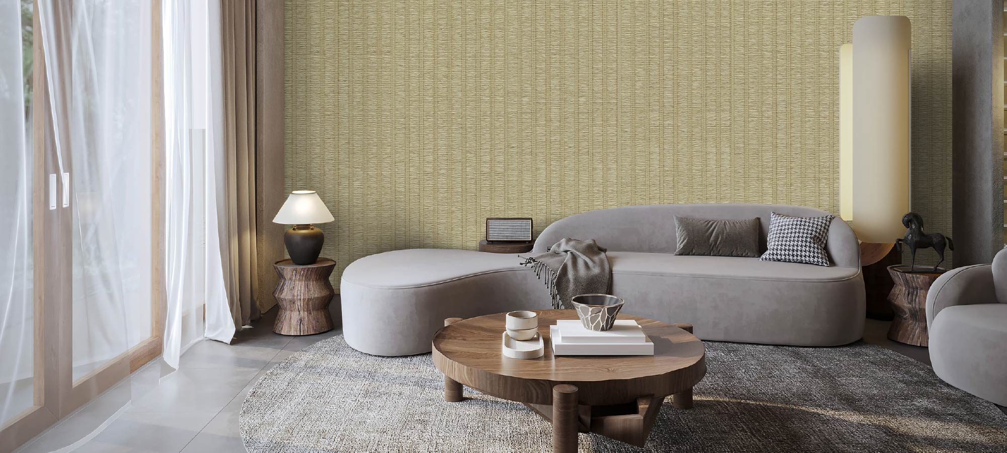 Contemporary living room with textured wallpaper, curved grey sofa, wooden coffee table, decorative side lamps, and natural light through sheer curtains.