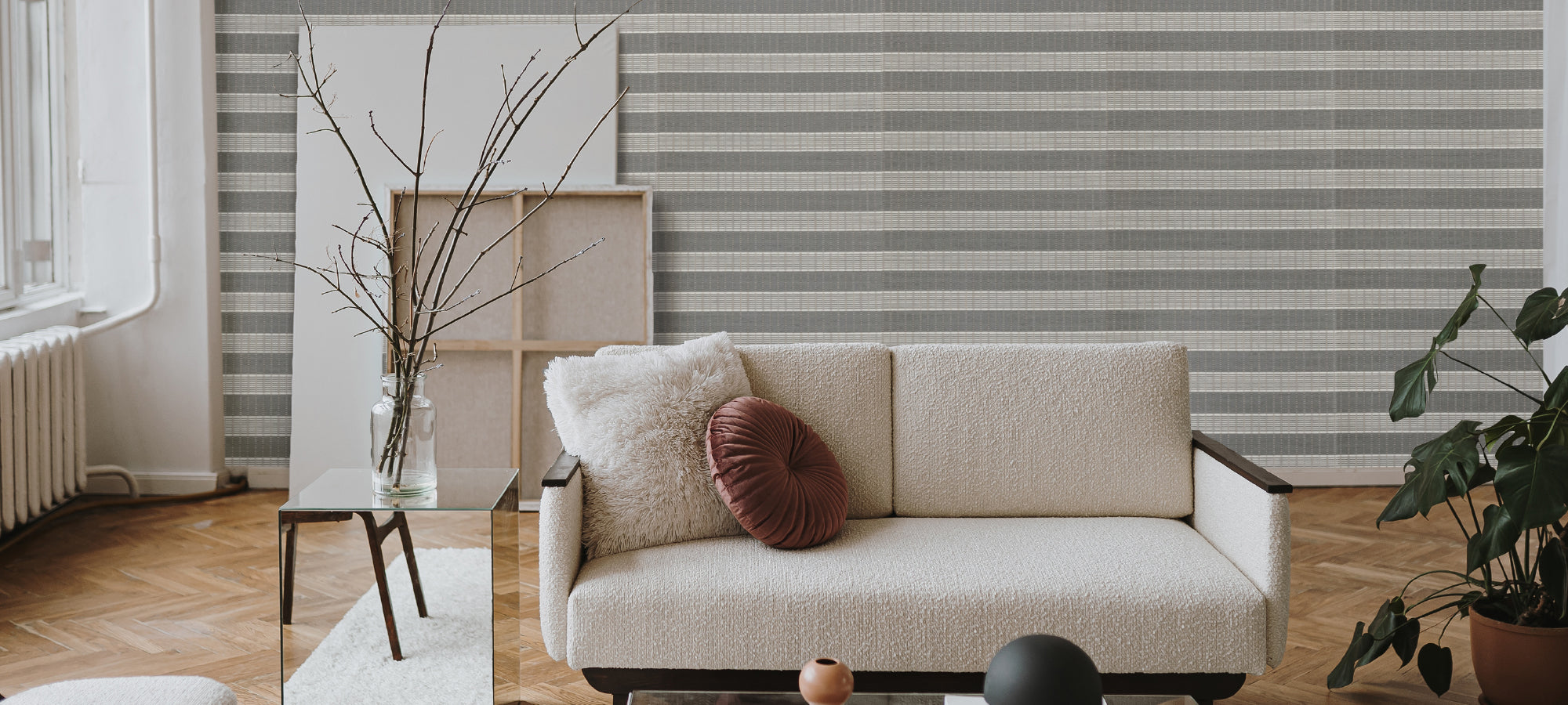 Stylish scandinavian living room with striped accent wall, modern cream sofa, glass coffee table, and indoor plants.