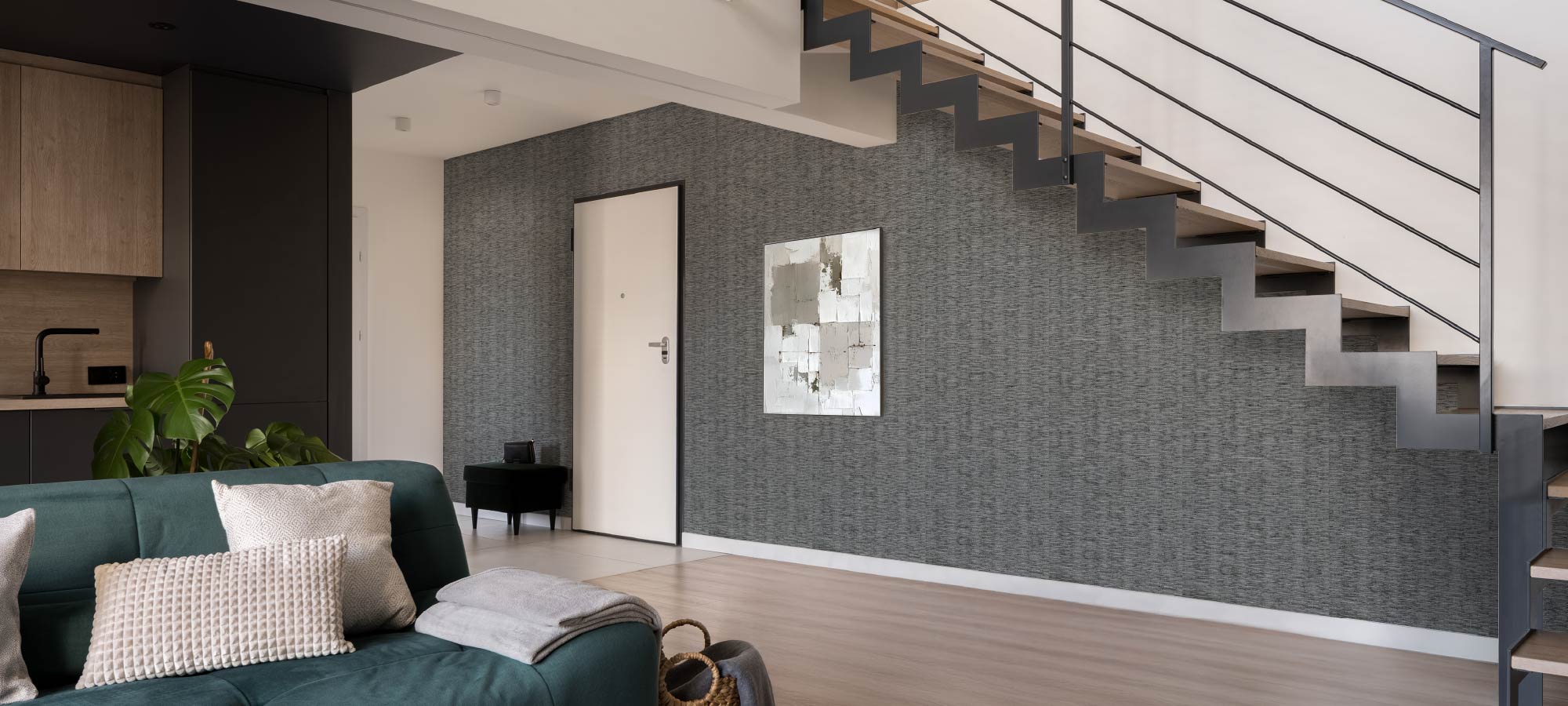 Contemporary living room featuring neutral textured wall, modern sofa with cushions, minimalist wooden furniture, and decorative indoor plants.