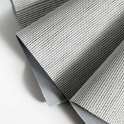Close-up of a textured vanilla-colored woven fabric with a gray backing, showing fine parallel lines and pleated folds.