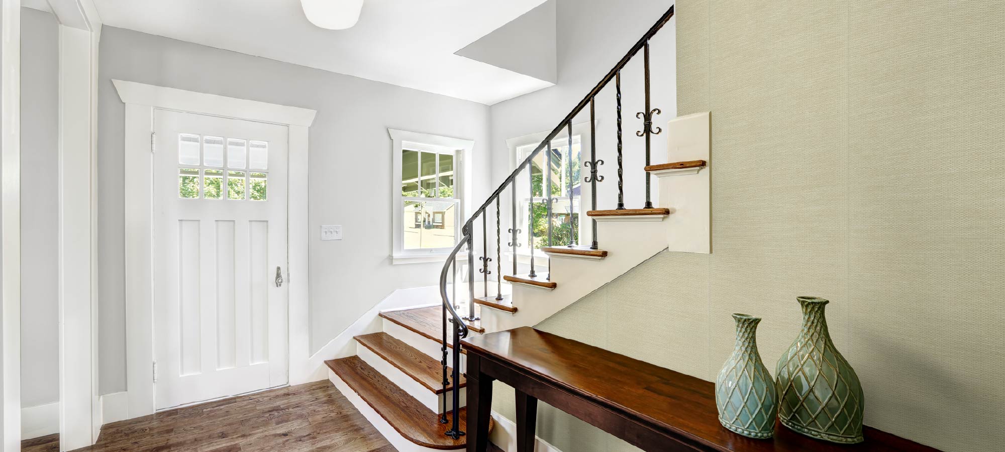 Staircase with a landing area featuring two green vases in a home interior.