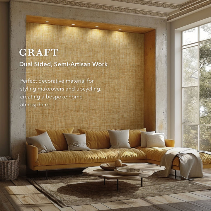 Modern living room with golden woven wallpaper, mustard yellow sectional sofa, neutral cushions, round wooden coffee table, and text overlay highlighting dual sided semi-artisan decorative fabric.