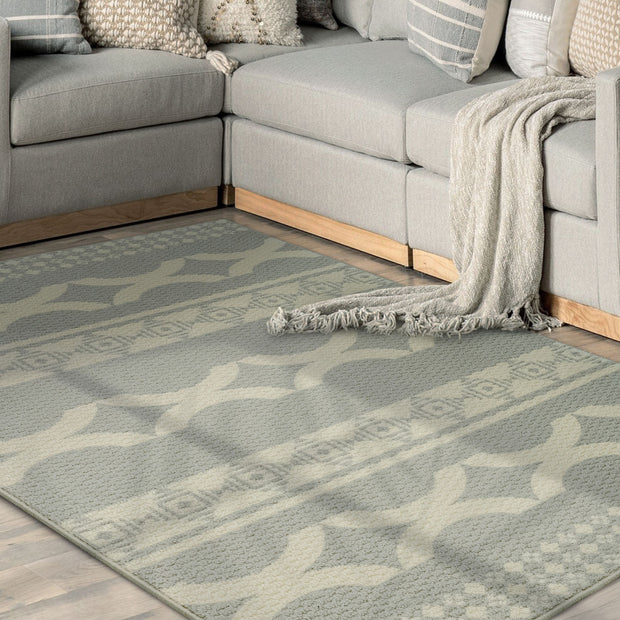 Gray sectional sofa with a patterned rug in a living room setting