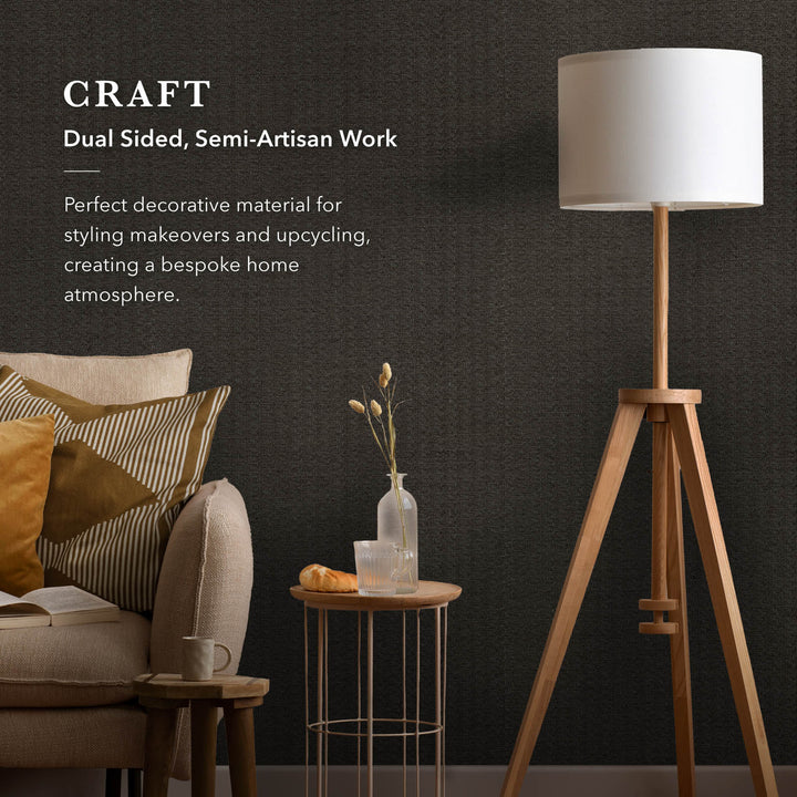 Modern living room with a tripod lamp, sofa, and small table against a dark wall.