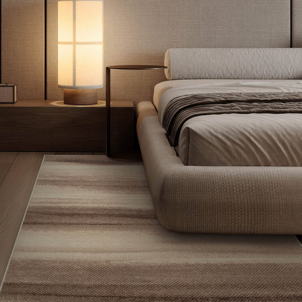 Modern bedroom with a bed, nightstand, and lamp on a striped rug.