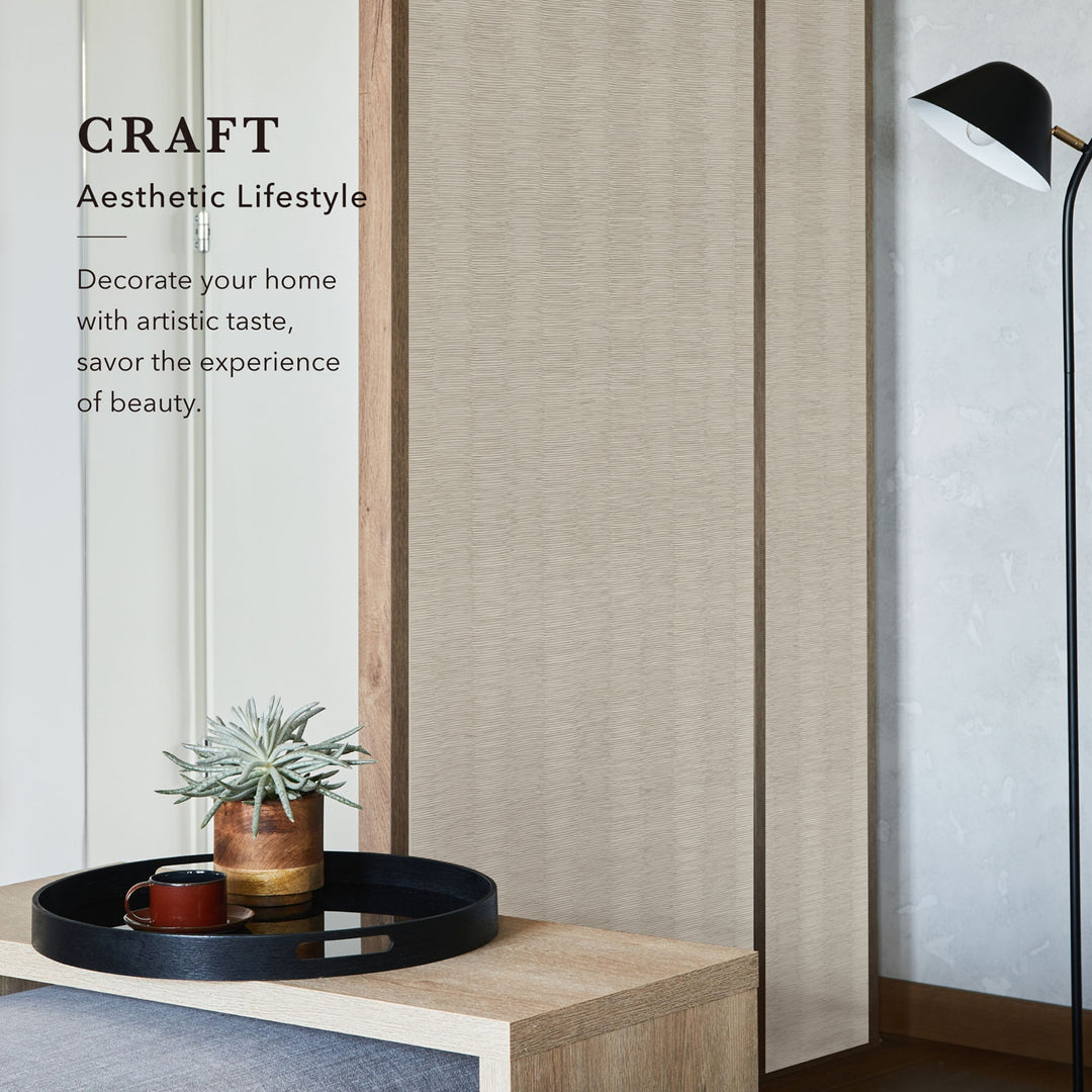 Decorative setting with a plant, tray, and lamp against a textured wall.