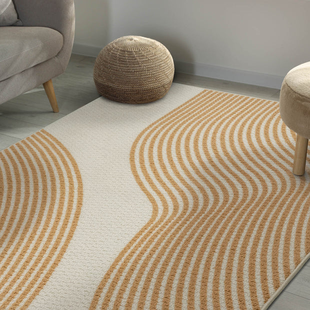 Rug with wavy brown pattern in a room with a gray sofa and wooden stools.