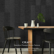 Dining area with wooden table and chairs against a dark pleated woven texture wall.