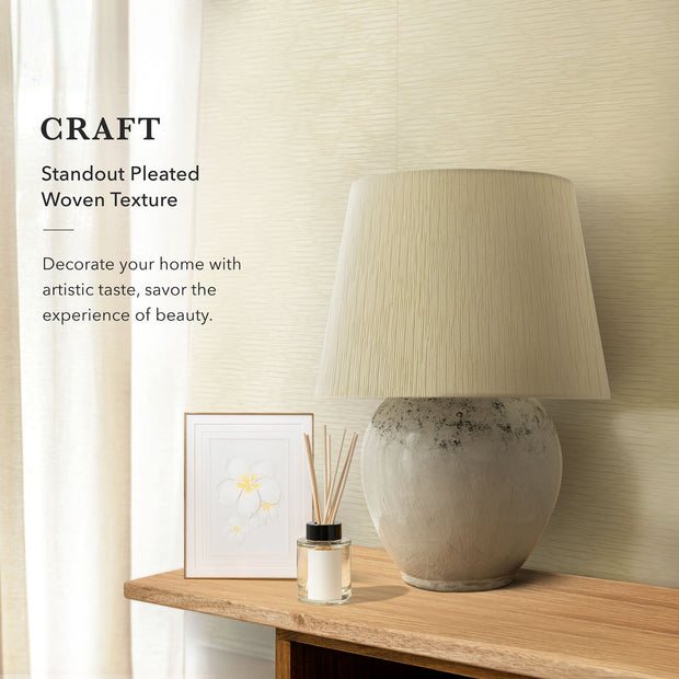 A modern, well-lit living space with a light beige, textured wall covering from GoDear Design. The image emphasizes the "CRAFT Aesthetic Lifestyle" by pairing the decorative material with a large, rustic ceramic table lamp, a framed floral print, and a wooden table. The text highlights the product's "Standout Pleated Woven Texture" and its ability to add artistic taste and beauty to a home.