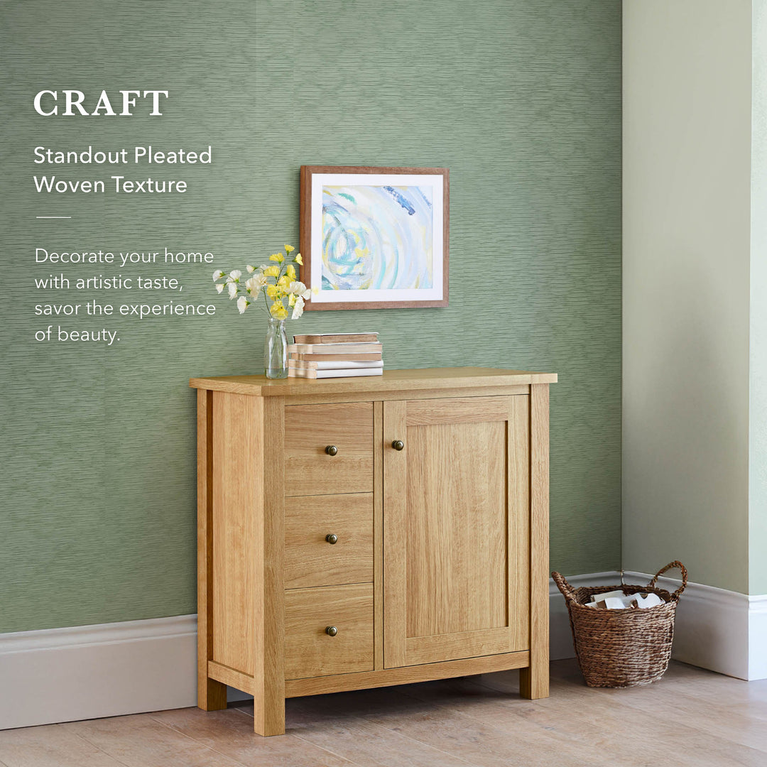 Modern living space with a green textured backdrop, wooden sideboard, framed abstract art, and woven storage basket.