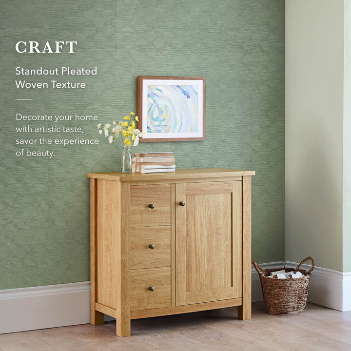 Modern living space with a green textured backdrop, wooden sideboard, framed abstract art, and woven storage basket.