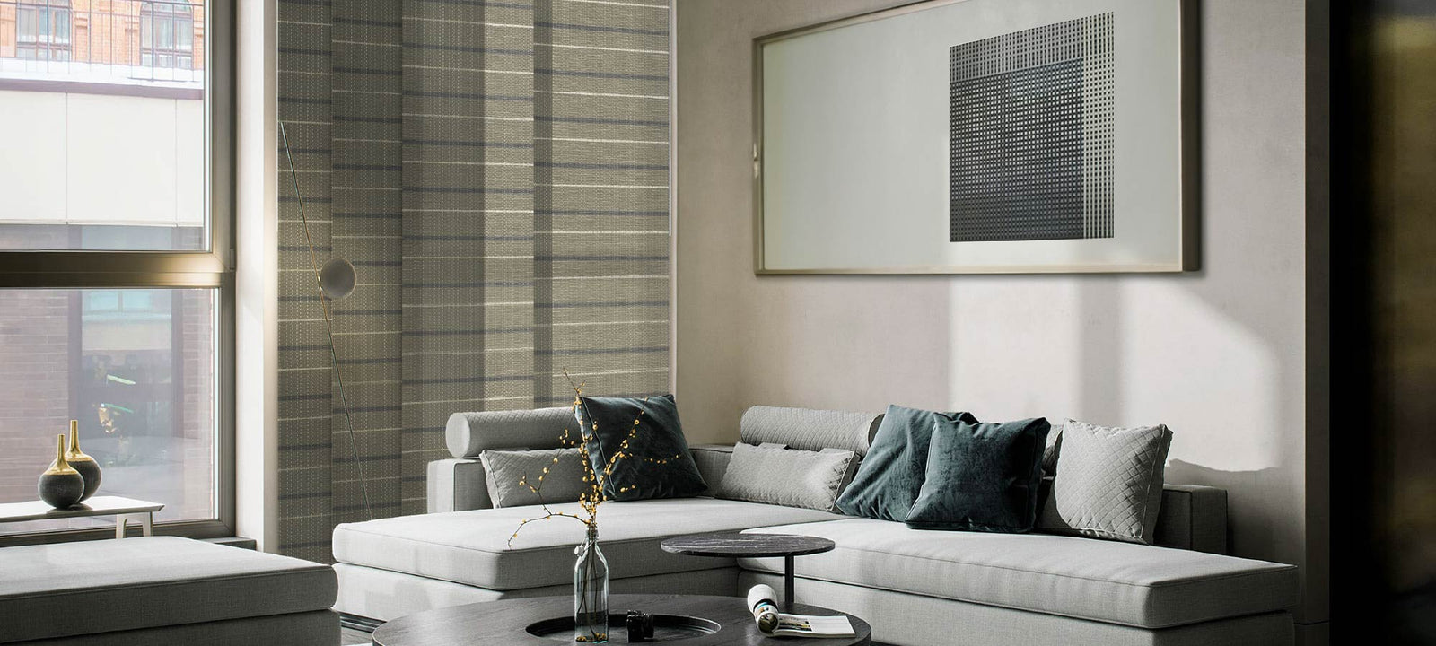 Cool neutral-tone panel track blinds filtering soft daylight in a contemporary living room with a gray sectional sofa, creating a calm and modern home atmosphere.