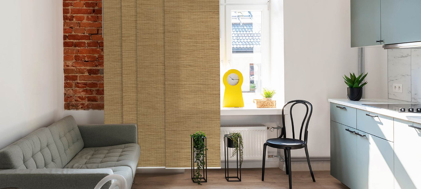 Pecan woven panel blinds in a warm beige tone, styled in a cozy neutral living room with wooden furniture and indoor plants.
