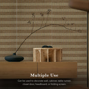 Decorative setup with a vase, branch, and wooden box against a striped wall.