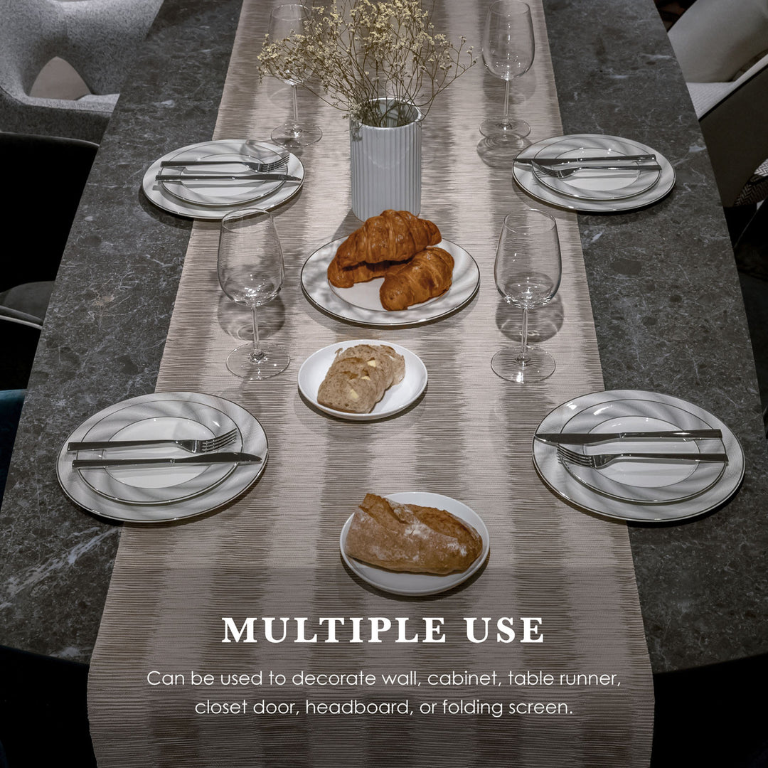Dining table setting with plates, croissants, and cutlery on a marble surface.