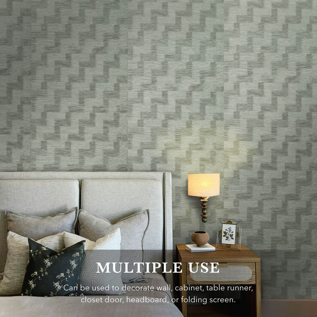 Bedroom with geometric patterned wall paper, bed, lamp, and nightstand.