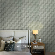 Bedroom with geometric patterned wall paper, bed, lamp, and nightstand.