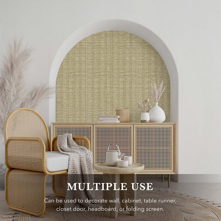 Decorative alcove with light beige textured vertical stripe wallpaper, rattan armchair, woven cabinet, and neutral-toned home decor accents.