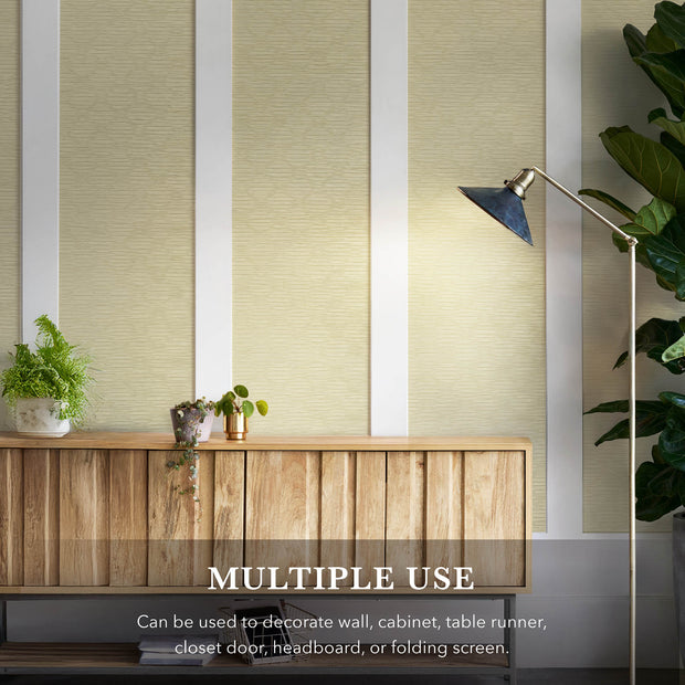 A modern, minimalist living space showcasing a wall covering from GoDear Design. The image features a wooden sideboard and various plants, with the light beige, woven wall covering serving as a backdrop. This accent material is highlighted for its "multiple use" potential, suggesting it can be used for walls, cabinets, or other DIY projects to create a natural and aesthetic home environment.