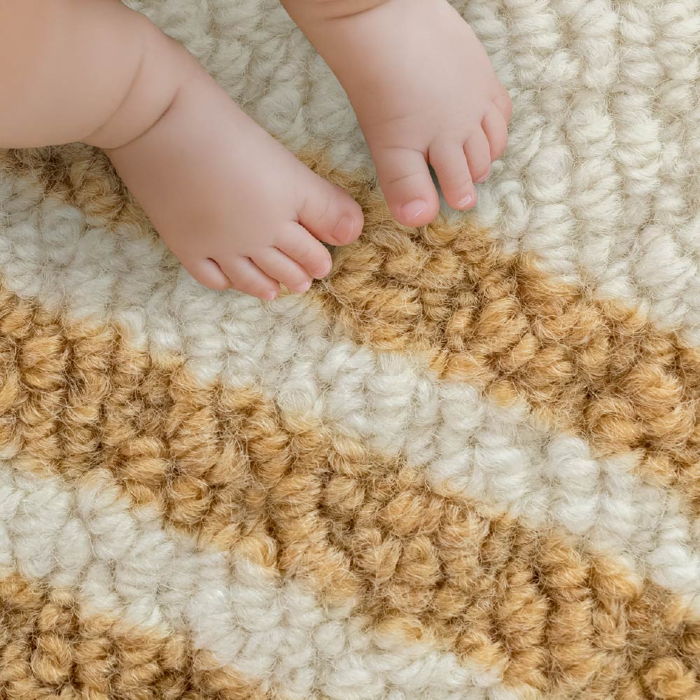 Close-up of a child's feet on a textured beige and brown carpet
