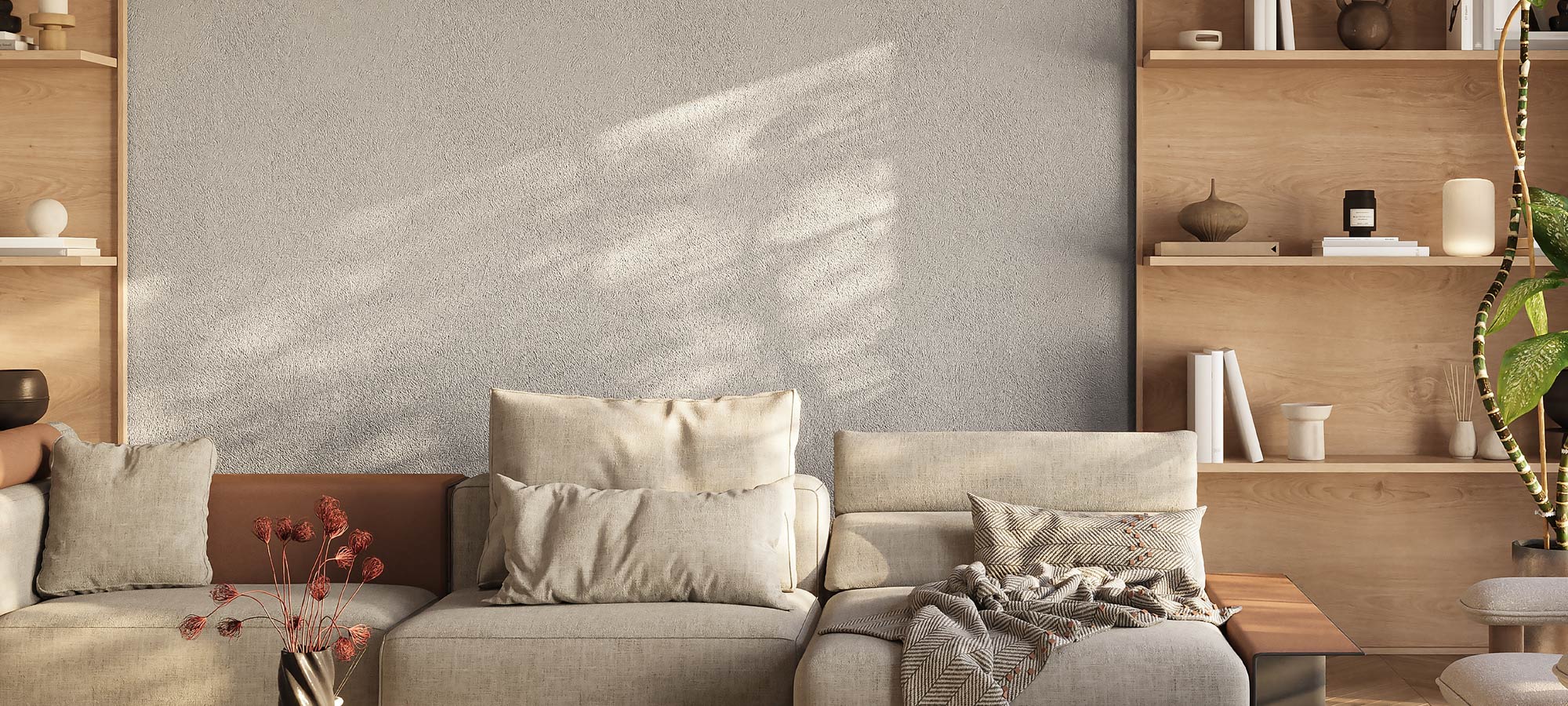 Modern living room with textured gray wall, beige sectional sofa, cozy throw blanket, wooden shelving with minimalist decor, and natural light.