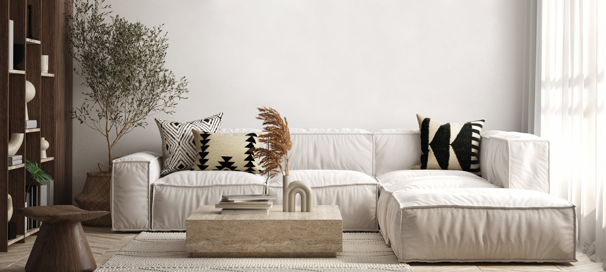 Modern minimalist living room with white sectional sofa, patterned throw pillows, wooden coffee table, and natural indoor plant.