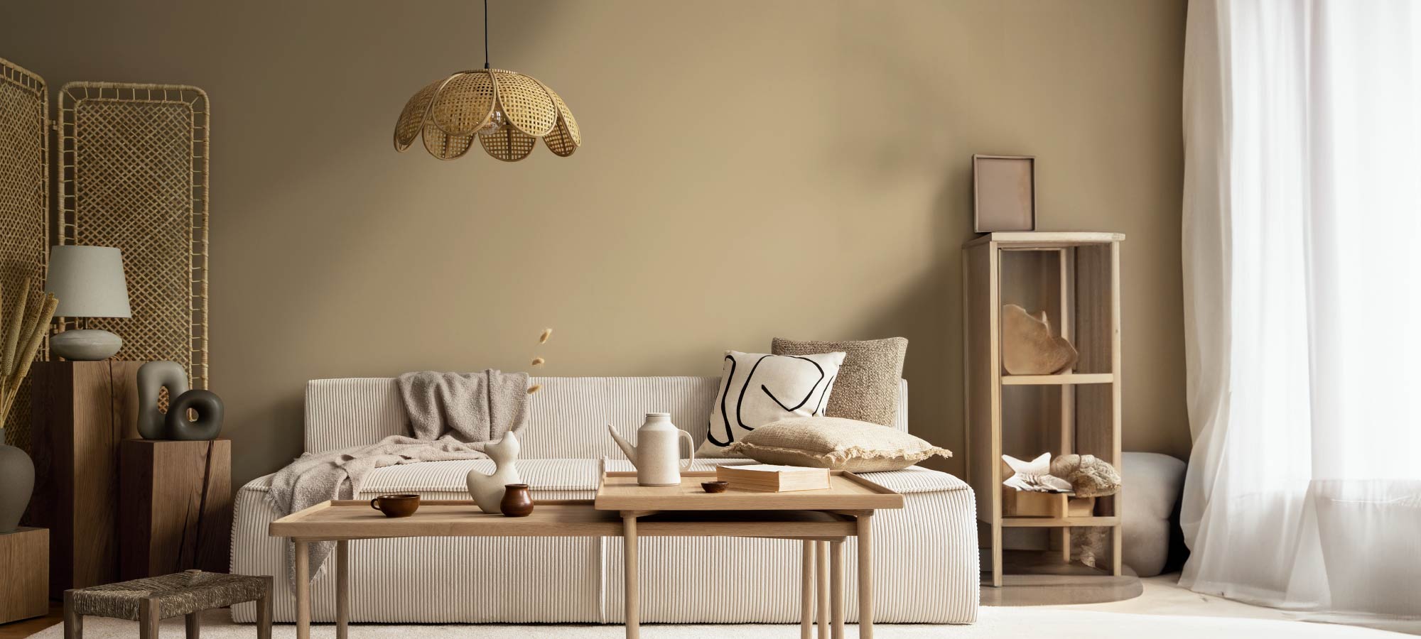 Minimalist living room with rattan pendant light, neutral sofa, wooden coffee table, and natural decorative accents.